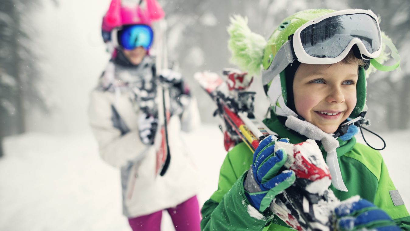 Little skiers carrying skis on a winter day